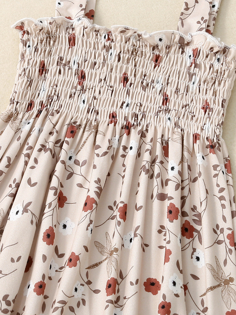 Baby jumpsuit with smocked bodice, floral print, and dragonfly accents.