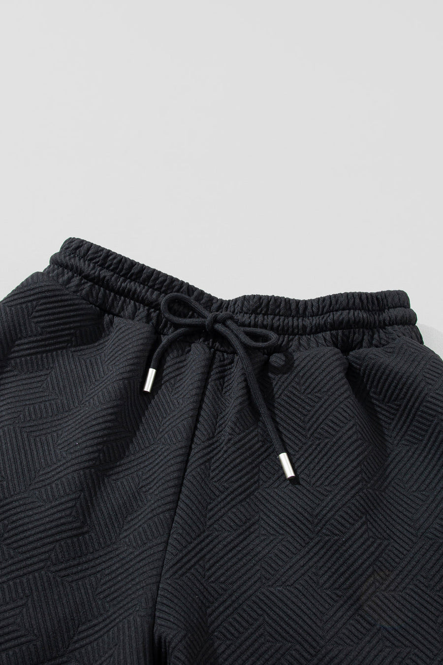 Black textured lounge pants with drawstring waist and silver-tipped ends.