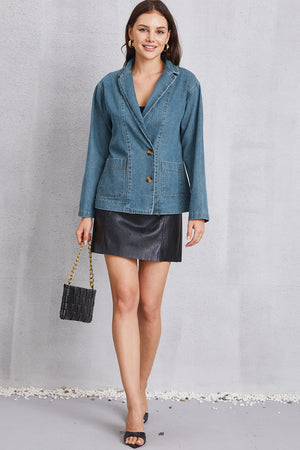 Denim blazer in medium wash with tailored seam detailing, two button closure, and flap pockets.