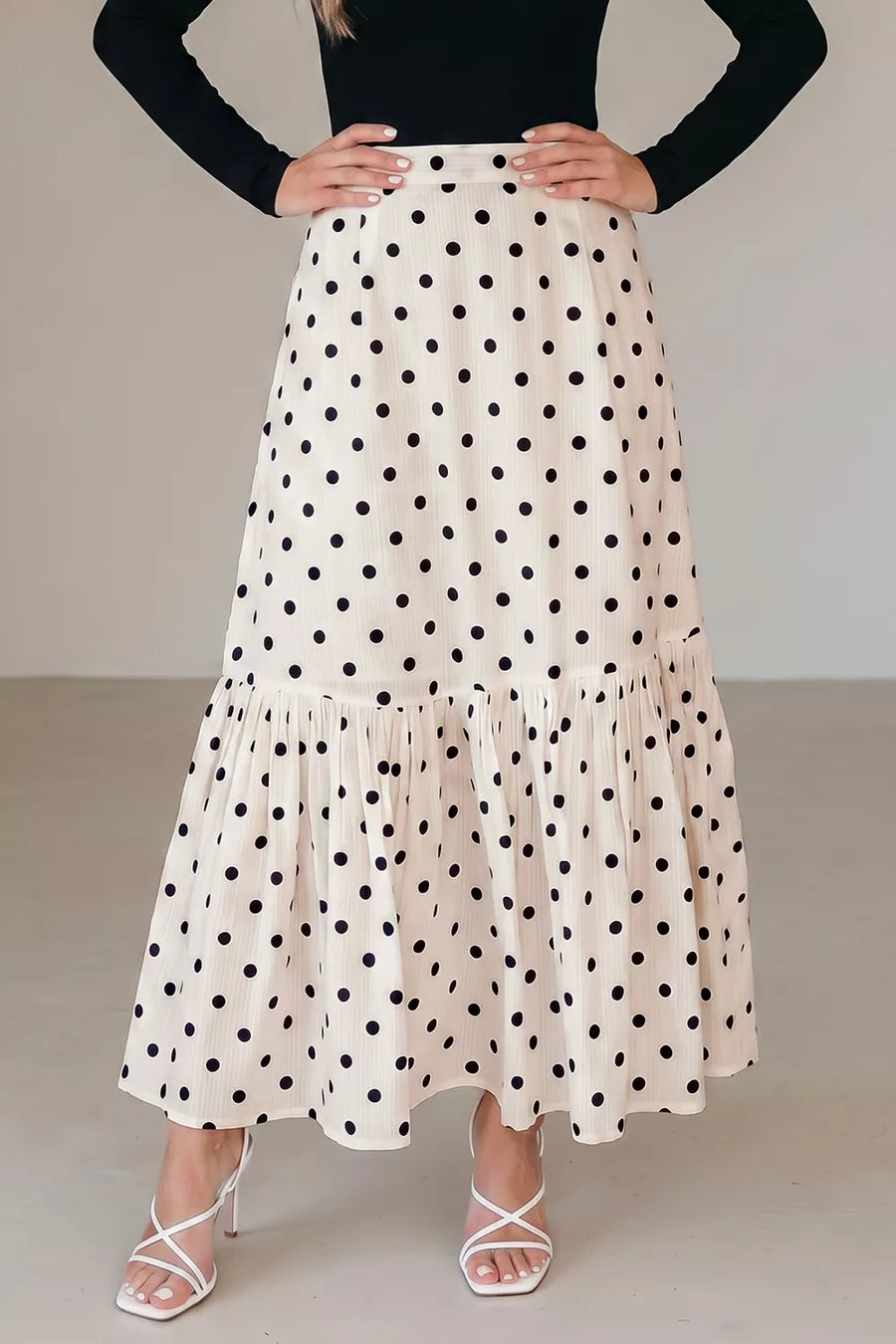 Chic polka dot maxi skirt in beige with a ruffled hem and subtle vertical stripes.