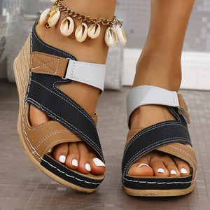 Colorblock crossover wedge sandals in brown, black, and white with white stitching and a seashell anklet.