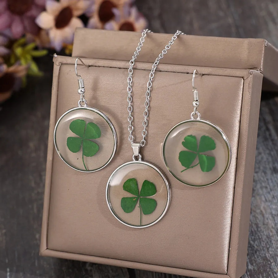 Pressed clover resin jewelry set with green four-leaf clovers in clear round pendants and silver chain.