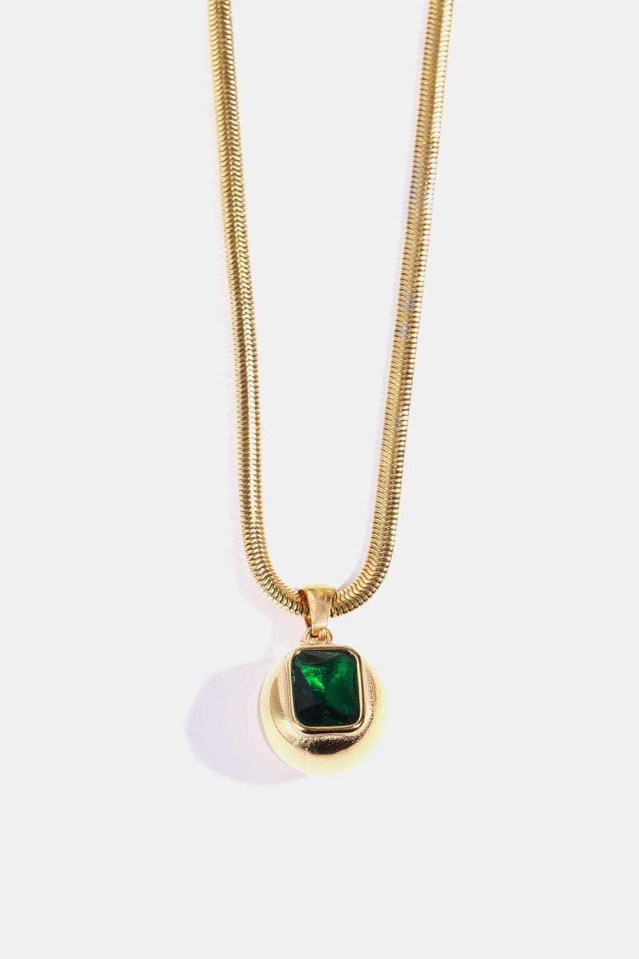 Gold necklace with a round pendant featuring a square dark green stone.