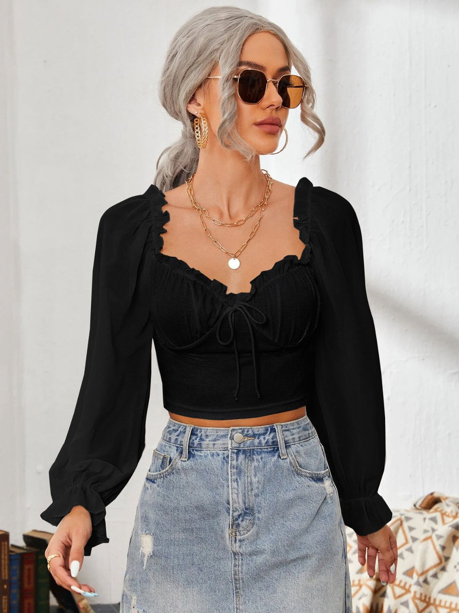 Black bustier blouse with sweetheart neckline, tie front, and puff sleeves.