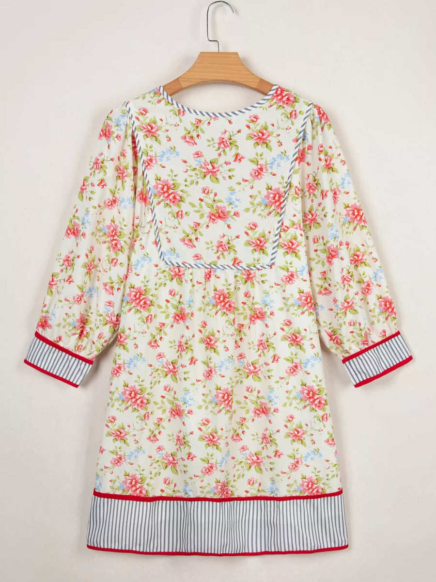 Floral cotton dress with puff sleeves, contrast trim, and striped hem.