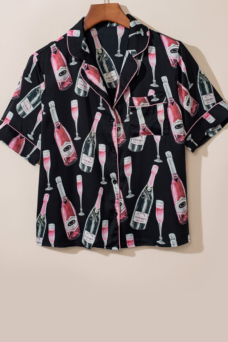 Black silk pajama top with champagne bottle and glass print, pink piping, and short sleeves.