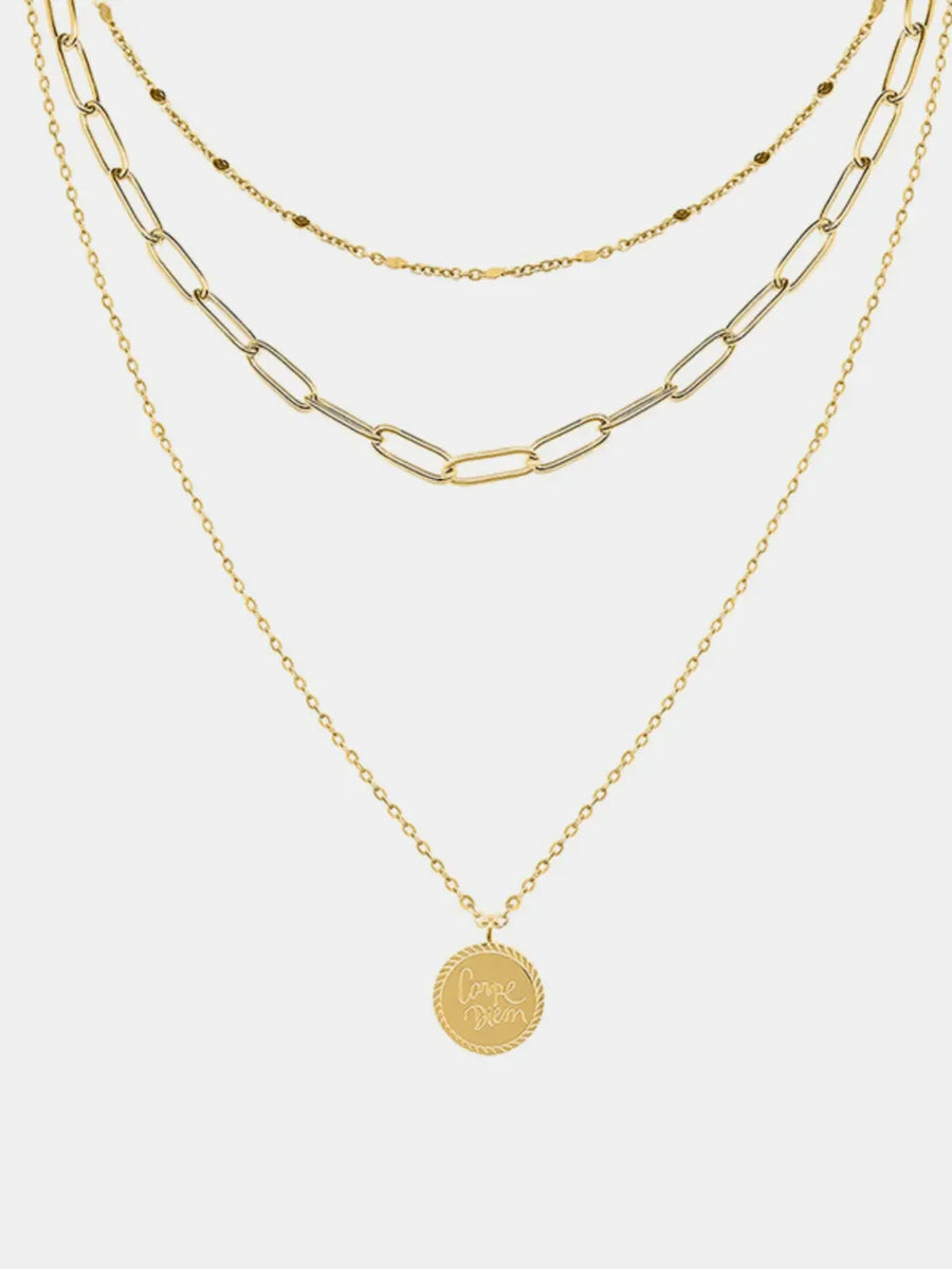 Gold layered chain necklace with a round pendant engraved with "Carpe Diem" text.