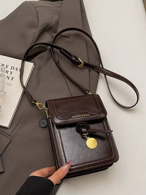 Sleek mini pu leather crossbody bag in deep red with gold charm detail.
