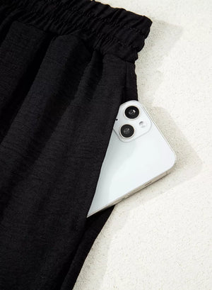 Black relaxed wide-leg maternity pants with drawstring waist and pocket detail.