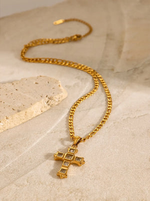 Gold cross pendant necklace with clear zirconia accents on a figaro chain.