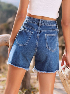 Medium wash denim shorts with frayed hem and classic five-pocket styling.