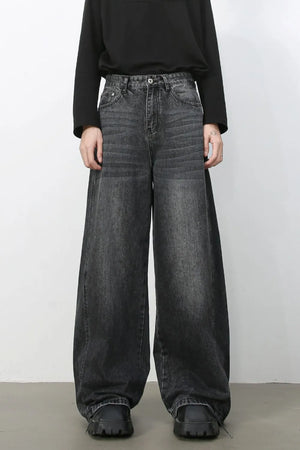 Dark wash denim trousers with exaggerated wide legs and a relaxed fit.