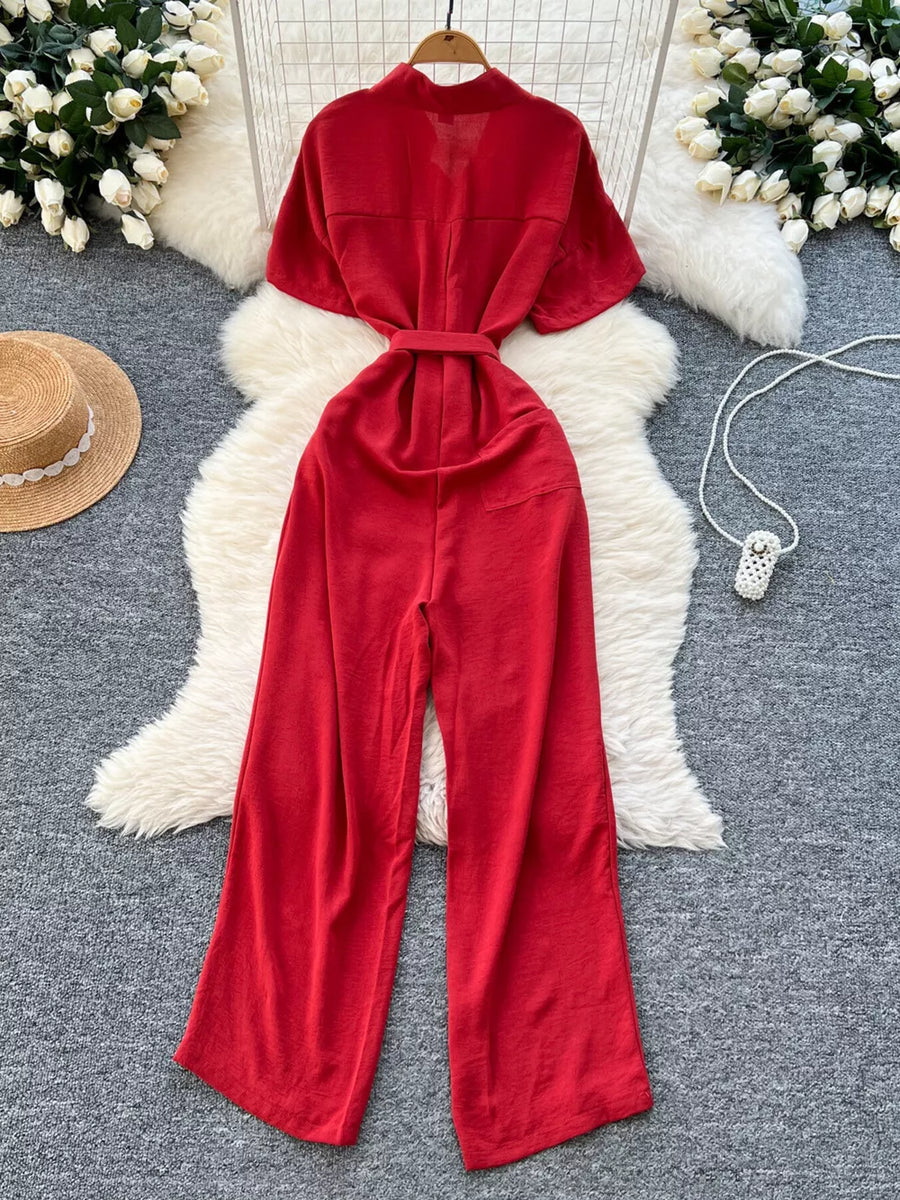 Red belted wide leg romper with short sleeves and mock neck.