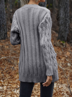 Grey cable knit cardigan with textured sleeves and ribbed hem.