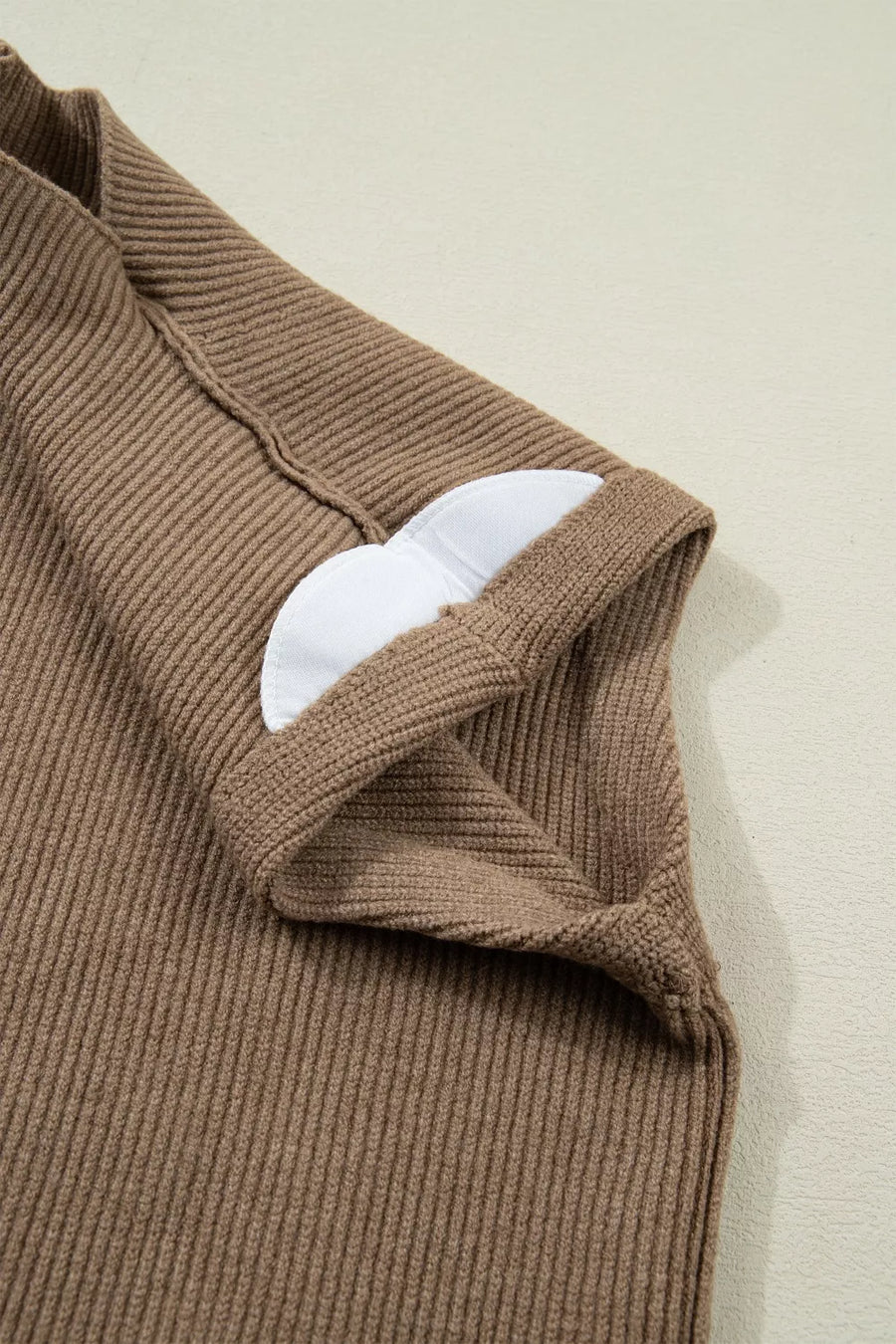 Brown ribbed knit mock neck sweater vest with white padded cups visible at the neckline.