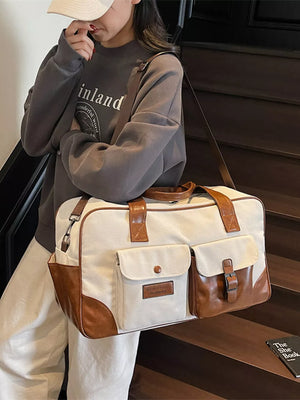 Sophisticated cream canvas travel bag with brown leather trim and multiple pockets.