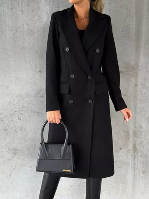 Black double-breasted longline trench coat with button detail and lapel collar.