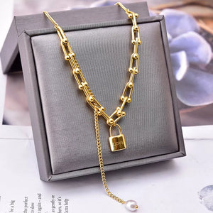 necklace in gold featuring lock pendant and draped fit