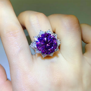 Amethyst sunburst moissanite cocktail ring with a large deep purple center stone and clear accent stones.