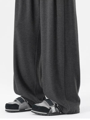 Dark gray relaxed fit drawstring sweatpants with pockets, shown on a man wearing sandals.