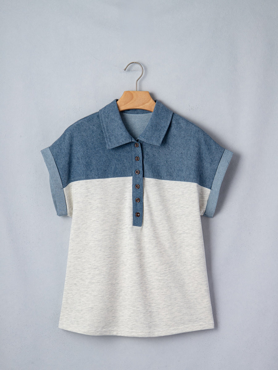 Two-tone denim polo shirt with button placket and rolled sleeves.