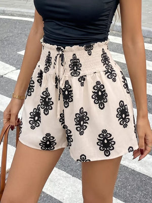 Cream shorts with black medallion print, smocked waist, and drawstring detail.