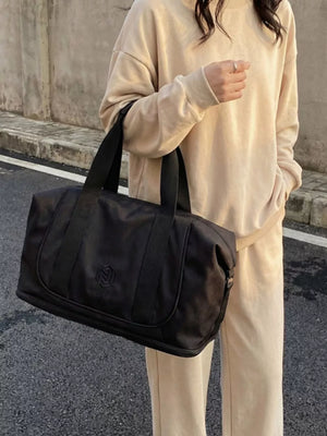 Black duffel bag with black straps and embossed logo detail.