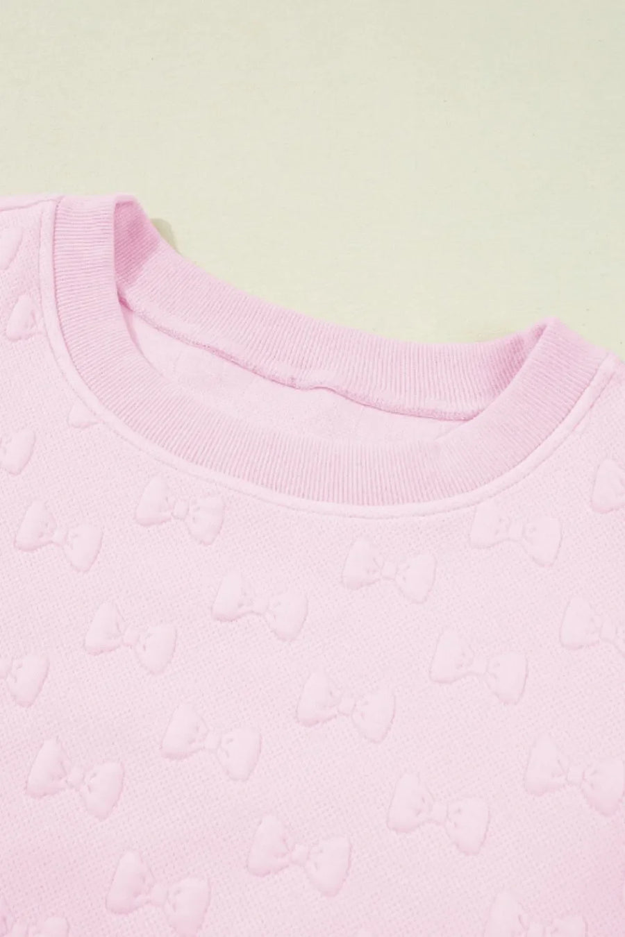 Blush pink loungewear set with embossed bow pattern and crew neck.