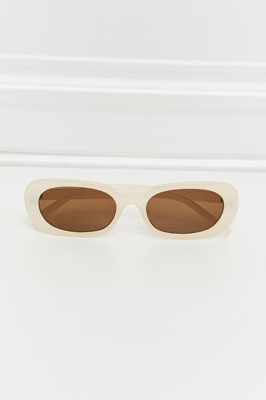Cream oval sunglasses with sunset brown lenses and a matte finish.