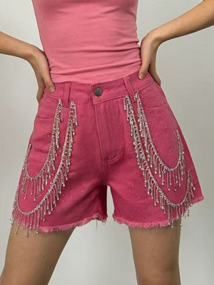 Fuchsia pink denim shorts with rhinestone chain fringe detail and frayed hem.