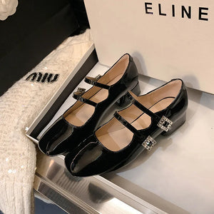 Black patent leather double strap Mary Janes with square toe and crystal buckles.