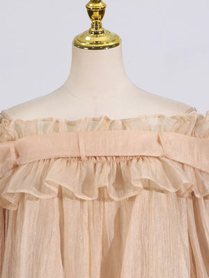 Champagne off-shoulder maternity blouse with ruffled neckline and billowy sleeves.