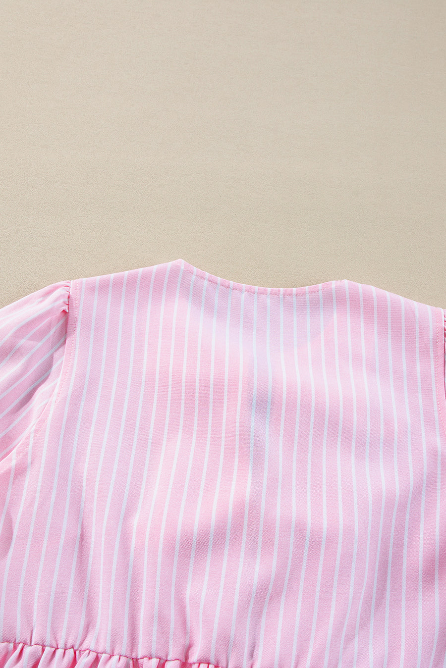 Blush pink striped peplum blouse with puff sleeves and ruffled hem detail.
