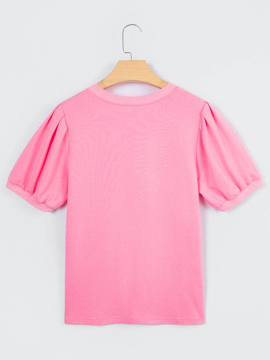 Pink cotton blouse with short puff sleeves and a round neckline.