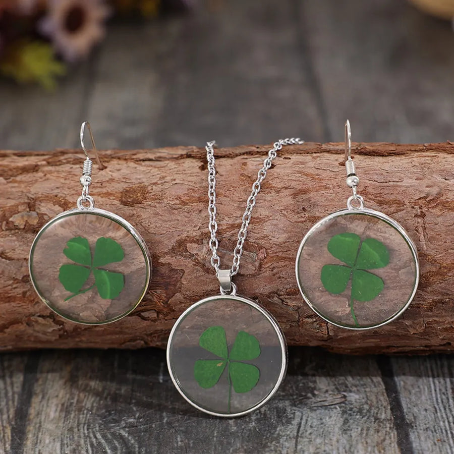 Pressed clover resin jewelry set with green four-leaf clovers in round pendants and earrings.