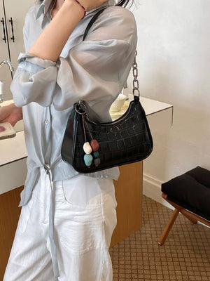 shoulder bag in black featuring textured and curved baguette fit