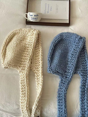 Cozy wool earflap beanie hat in off-white and blue, chunky knit with long ear flaps.