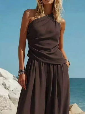 Brown one-shoulder top and wide-leg pants set with a draped neckline and pleated pants.