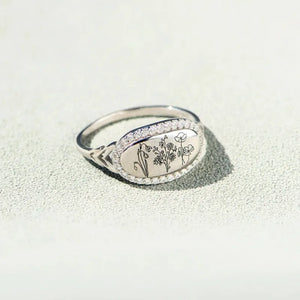 Silver signet ring with engraved floral design and cubic zirconia band