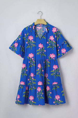Blue tiered cotton dress with pink floral print, flutter sleeves, and tie neck.