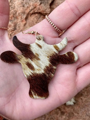 Cowhide silhouette drop earrings in brown with natural pattern, hanging from a gold hook.