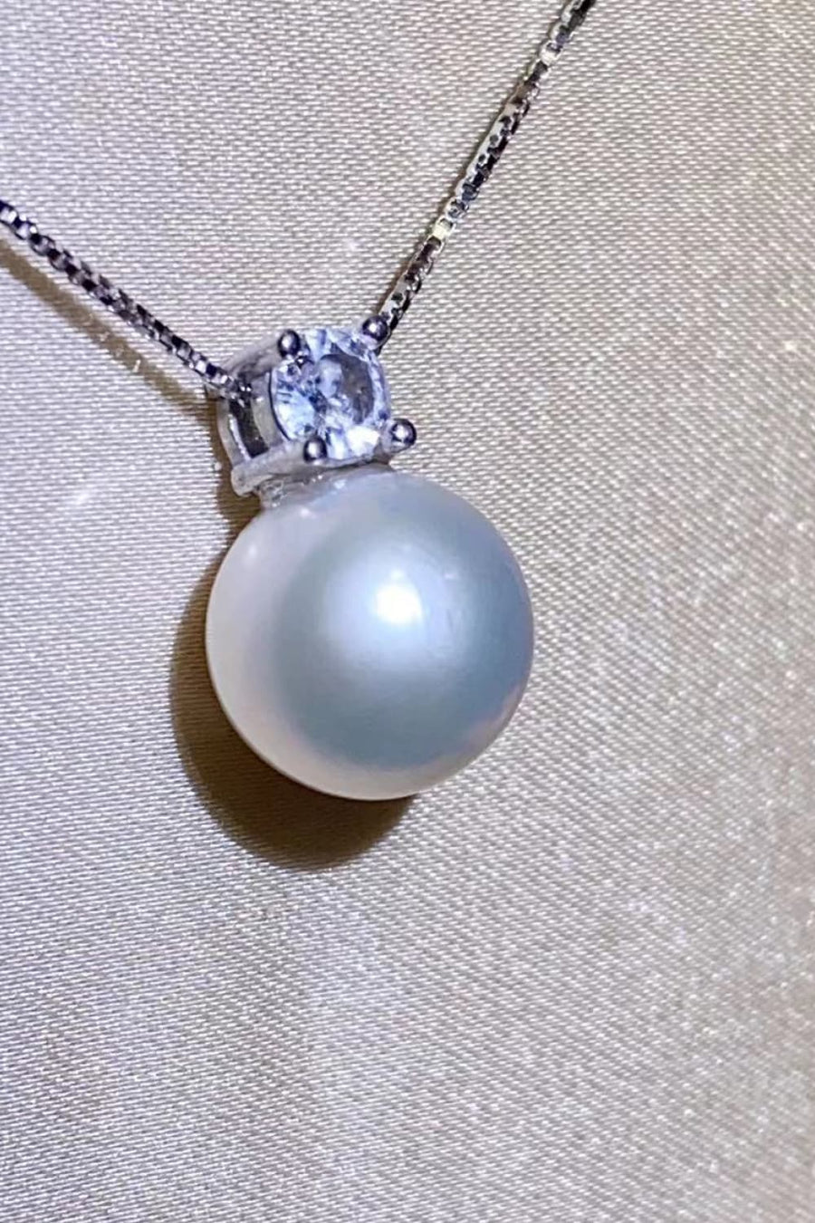 Solitaire pearl pendant necklace in silver with a clear stone accent on a delicate chain.