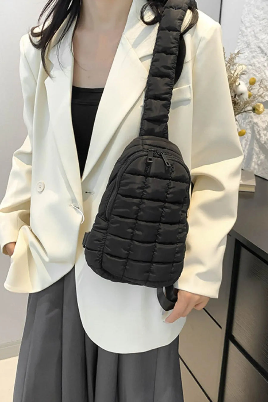 Black padded sling bag with quilted texture and top handle