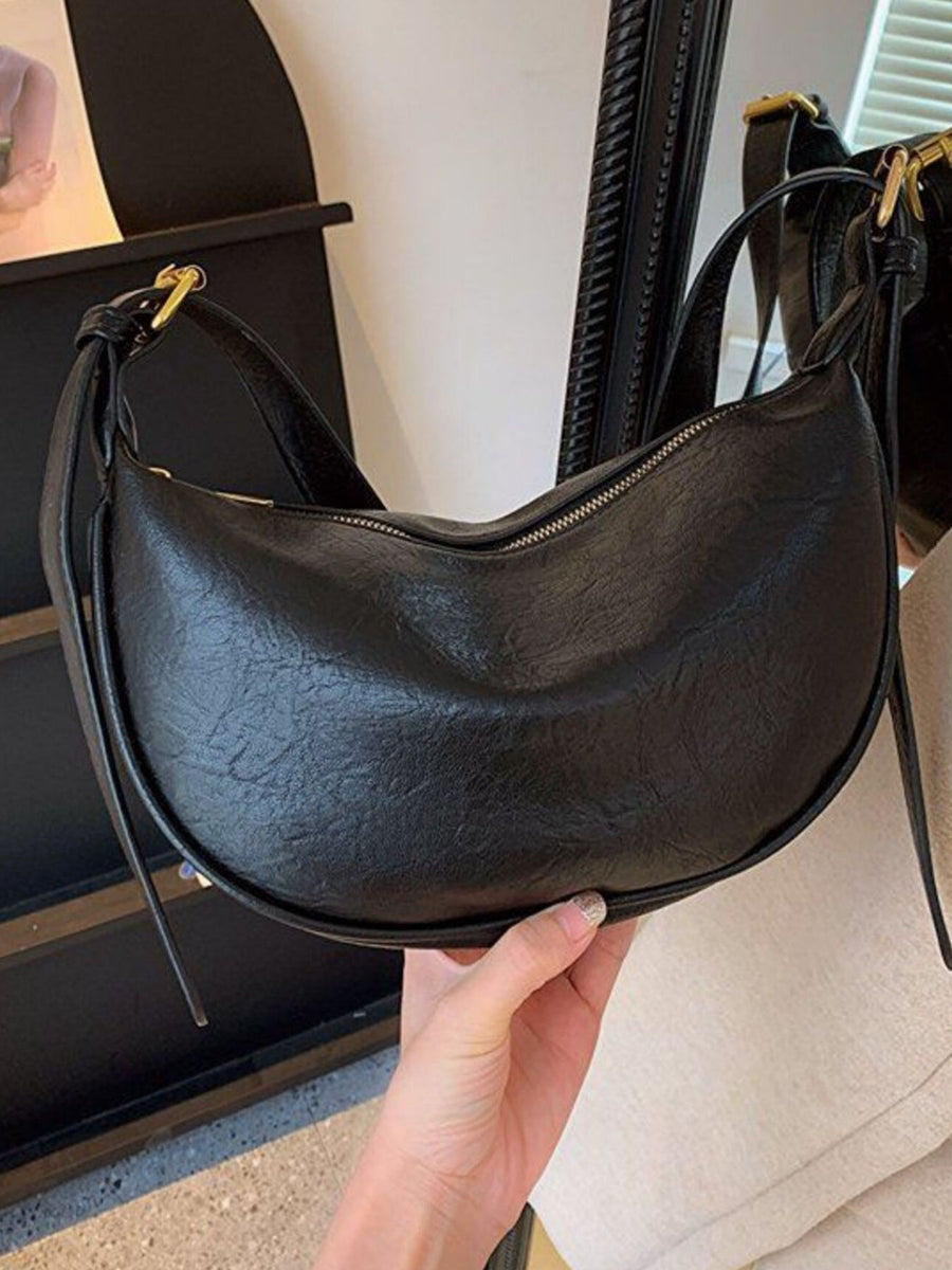 Black crescent shoulder bag with plush charm and adjustable strap