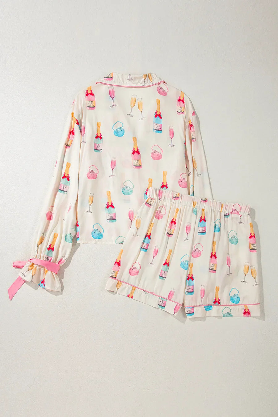 Champagne print silk pajama set in white with pink trim and bow details on sleeves.