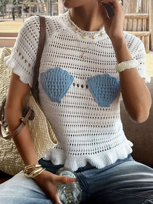 White crochet knit top with blue seashell appliqués and ruffled hem.