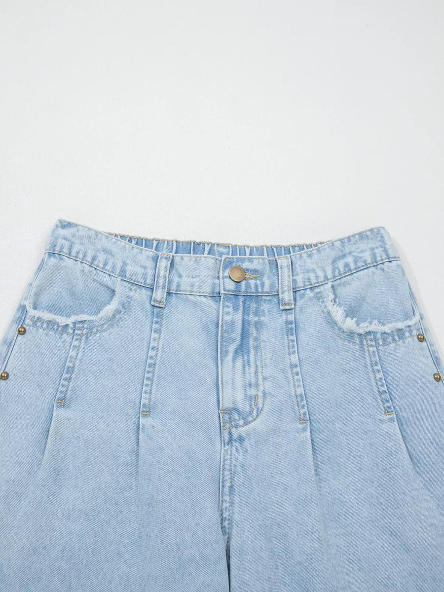 Light wash denim jeans with studded pockets and wide legs.