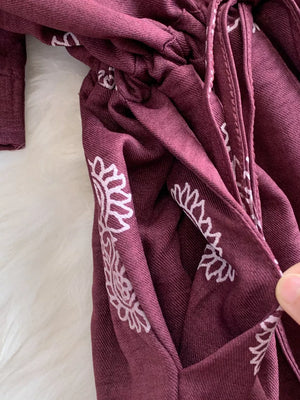 Burgundy maternity joggers with white floral print and drawstring detail.