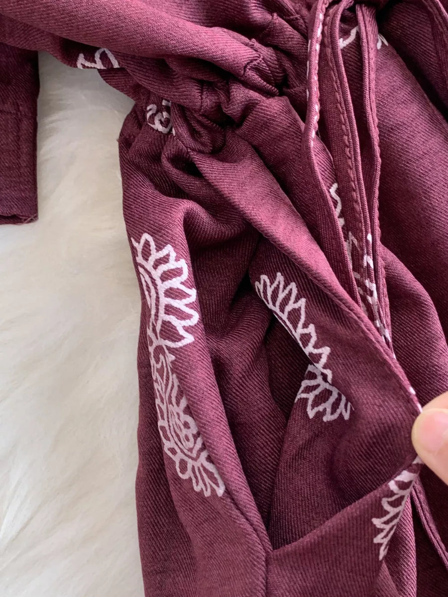 Burgundy maternity joggers with white floral print and drawstring detail.