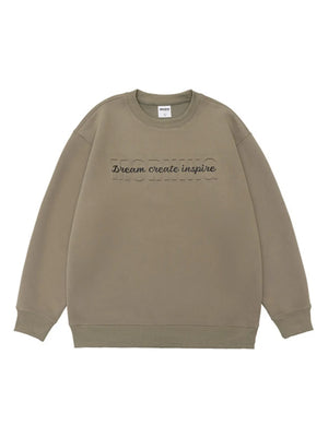 Oversized khaki crew-neck sweatshirt with embossed "MORNING" and "Dream create inspire" text.